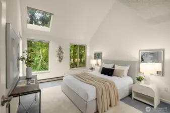 Airy primary retreat with soaring ceilings, skylight, and serene forest backdrop.