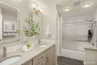Beautifully updated bath with dual sinks, ample storage, and sleek shower — accessible from both the primary bedroom and hallway.