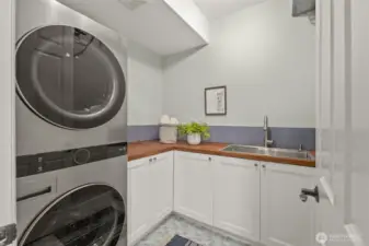 Convenient laundry/mudroom just off the garage with custom cabinetry/wood counters and utility sink.