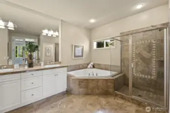 Primary bathroom with marble flooring, marble countertops and marble surrounding the bath.