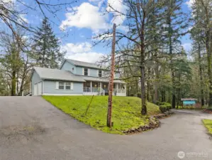 A pass through driveway in the photo below leads to the double wide gates and storage shed. The sloped driveway leads to the home. The City of Tumwater water meter and backflow lines are to the right of photo.
