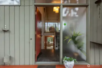 Dramatic front entry with stone tiled flooring, 3 50’s style ceiling lights,  and designer iron railing.