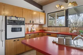 The kitchen, with its own artistic flair, has entertained many in this home's history. A seating counter and great views. Wood cabinets with unique hardware.