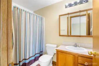 This 3/4 bath is in the primary bedroom with a shower, and has a single sink, with upper and lower cupboards.