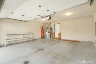 The two-car garage has shelving and a slightly elevated ramp going into the house.