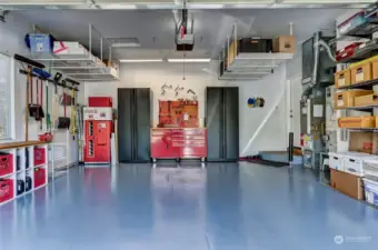 Absolutely spotless garage with a painted floor, hanging storage and side storage. (The freezer, black cabinets and work bench are excluded from the sale.)