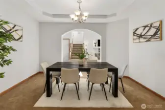 Dedicated dining area with tray ceiling surrounded by arch entryways