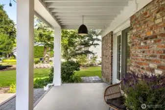 Covered patio space blends indoor comfort with outdoor living, perfect for morning coffee surrounded by greenery.