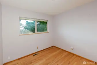 Bedroom with hardwood flooring and front yard outlook.