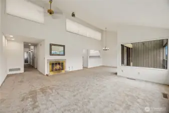 Living room with vaulted ceiling, ceiling fan, abundant natural light, and gas fireplace