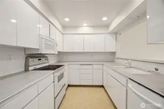 Spacious with a multitude of cabinet and counter space  Corian counters / tile backsplash / linoleum floor  Bright white cabinets with adjustable shelves & pull out lazy susan  Fridge, electric stove, dishwasher, and built-in microwave