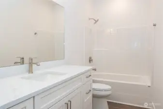 The Full Bathroom in the upstairs hallway boasts excellent storage space, quartz counters, a full bath/shower combo and luxury vinyl plank (LVP) flooring, blending modern style, durability and function.