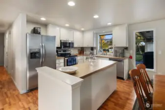 Open kitchen features recessed lighting, stainless steel appliances, and light cabinetry.