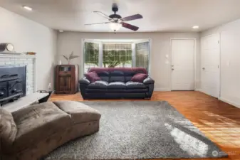 Living room features a large bay window, open layout, and cozy wood fireplace.