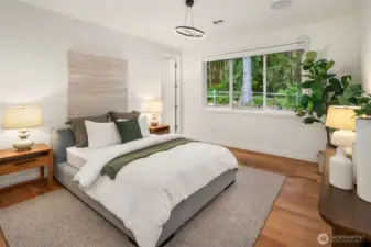 Primary bedroom on the main level enjoys tranquil views of the greenbelt and ultimate privacy