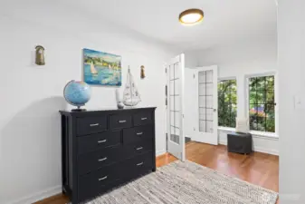 This bedroom features a spacious play area, a cutout with French doors leading to a sleeping nook, and an en suite bathroom for convenience and privacy.