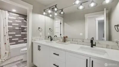 Guest bathroom with double sinks and private shower/tub and toilet.