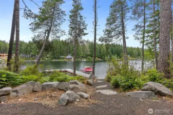 A thoughtfully landscaped path leading to the boat dock and a view of Tee Lake from the future home site.  The presence of full-time residents and new homes being built indicates a vibrant and desirable community.