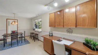 The functional desk nook paired with a light-filled dining space is perfect for both meals and productivity.