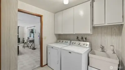 Bright laundry area with plenty of cabinetry and convenient utility sink.
