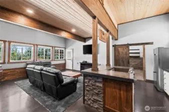 Open layout connecting kitchen, dining, and living space with vaulted wood ceilings.