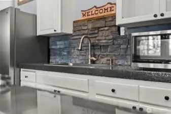 Kitchen detail featuring stone backsplash, stainless appliances, and rustic touches.