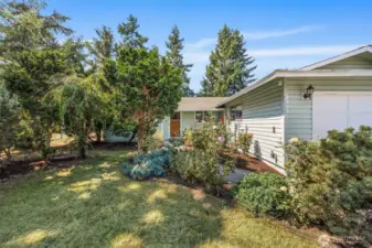 Welcoming exterior entry framed by mature trees, offering natural privacy and a peaceful, shaded approach to the home.