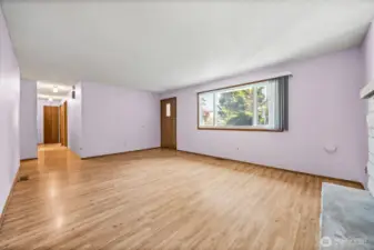 Spacious living room just off the entry, featuring a cozy wood burning fireplace and plenty of natural light - perfect for relaxing or entertaining.