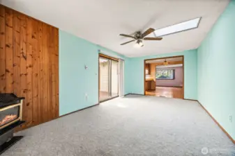 Cozy and flexible bonus room featuring a gas fireplace, ceiling fan, and skylight for year-round comfort and natural light. Direct access to the deck makes it perfect for entertaining or relaxing with family.
