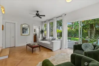Bathroom adjacent to the living area, with large sliding doors opening to a spacious patio surrounded by mature landscaping- perfect for outdoor gatherings!