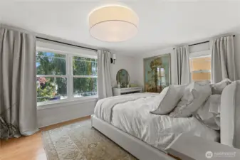 Primary bedroom filled with natural light, offering a serene retreat with views of mature landscaping