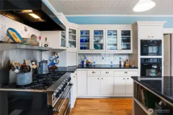This Victorian inspired kitchen includes real hardwood flooring, tile backsplash, custom cabinetry, and a Blue Star gas cooktop.