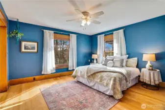 The primary bedroom stretches across the front of the home with windows overlooking the front yard and the tall neighborhood trees. Fir floors and hemlock millwork continue on this upper level of the home.
