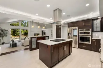 Quartzite counters and rich wood cabinetry bring depth, while the double ovens, gas cooktop, and built-in fridge offer ease at every turn.