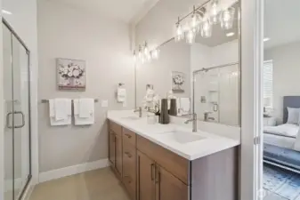 Primary bath features dual undermount sinks with Moen satin nickel high-arc faucets, quartz vanity with  framed mirror & satin nickel lighting