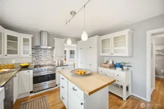 Pretty kitchen features a gas Viking range, stainless Bosch dishwasher, ample cabinets covered with quartz counters and nice butcherblock covered island.