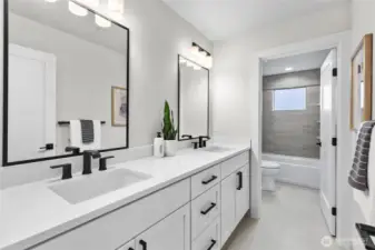 This stylish bathroom features a double-sink vanity with matte black fixtures and framed mirrors, offering both elegance and functionality. The attached tub and shower area, accented with soft tile tones and natural light, complete the space with a clean, contemporary feel.