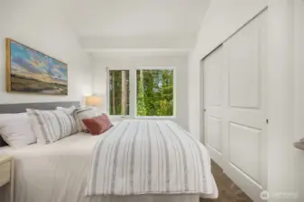 Primary bedroom with a peaceful outlook, looking out to lush, temperate forest views.