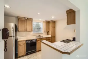 The efficient kitchen features a small tile bar and lots of light.