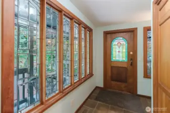The foyer is adorned with a leaded glass window and a stained glass door.