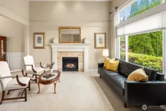 Formal Living Room with beautiful gas log fireplace, dramatic high ceilings, and large picture window looking into the front yard.