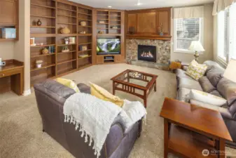 A great room style Family Room w/ custom built in bookcases & shelving,  beautiful wall paneling, and a built in desk area, and lovely gas log fireplace! This room is just off the Kitchen Area.