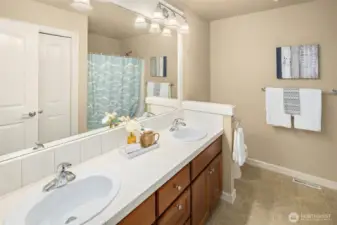 A large hall bathroom upstairs features dual sinks & a shower over the tub, and a linen closet