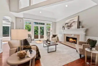 Just off the entry, find an elegant living room with soaring ceilings, a cozy gas fireplace, and double doors out to a wraparound deck.