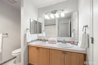 Double vanity, tiled floors, counters and tub/shower surround.