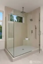Primary suite walk-in glass surround shower with dual rain shower heads.