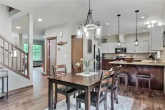 View to the kitchen and dining area from the family room. Updated light fixtures including LED bulbs, powder room and coat closet in the hall, entry to your left.