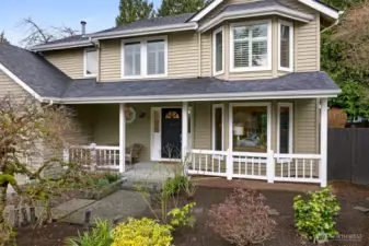 The covered front porch offers a sheltered entry and a comfortable place to pause before heading inside. Decorative glass at the front door adds natural light and a polished welcome.