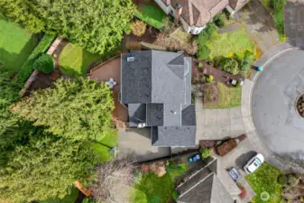An aerial view highlights the rare combination of a large lot, cul de sac placement, and deep evergreen buffer for privacy. The oversized deck, patio, and sport court layout shows how thoughtfully the outdoor spaces are designed for real life use.