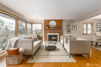 Spacious main living area with wall of windows to allow lots of natural light. Hardwood floors and cozy gas fireplace add charm and warmth. Notice the connection to the formal dining area....